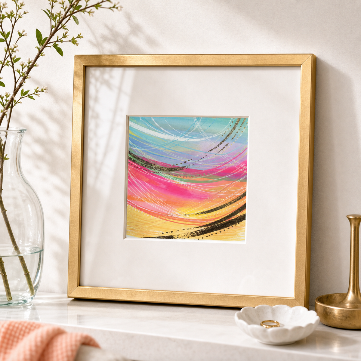 Abstract Stripe by Amber Miro, original watercolor in pink, peach, and mint, leaning in a gold frame beside a glass vase