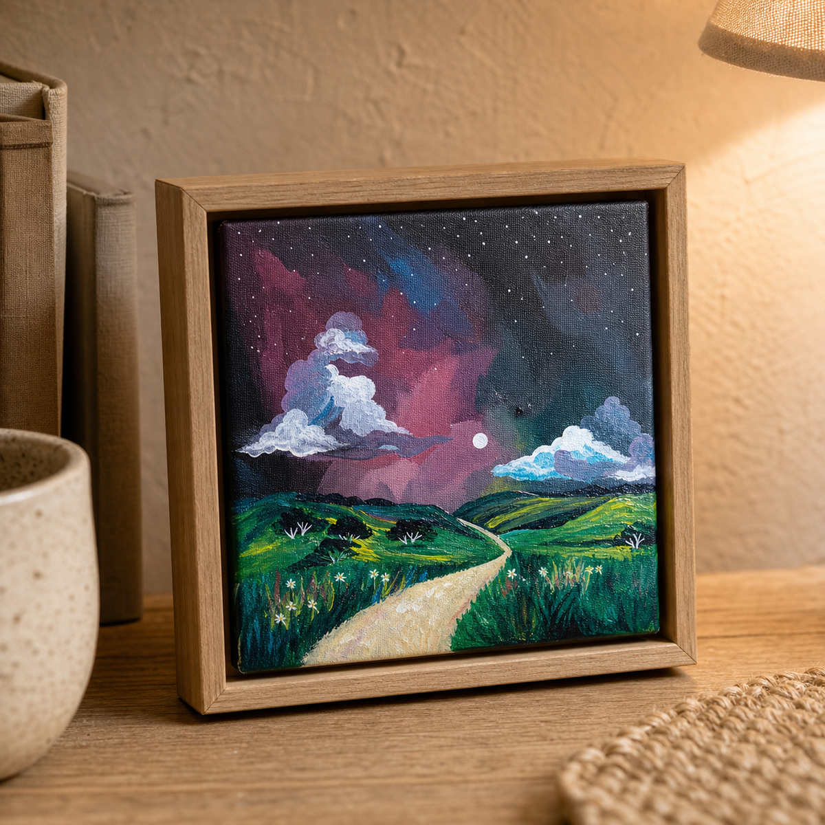 Aurora by Amber Miro, original night sky painting in pink, violet, and green, in a wood floater frame on a tabletop