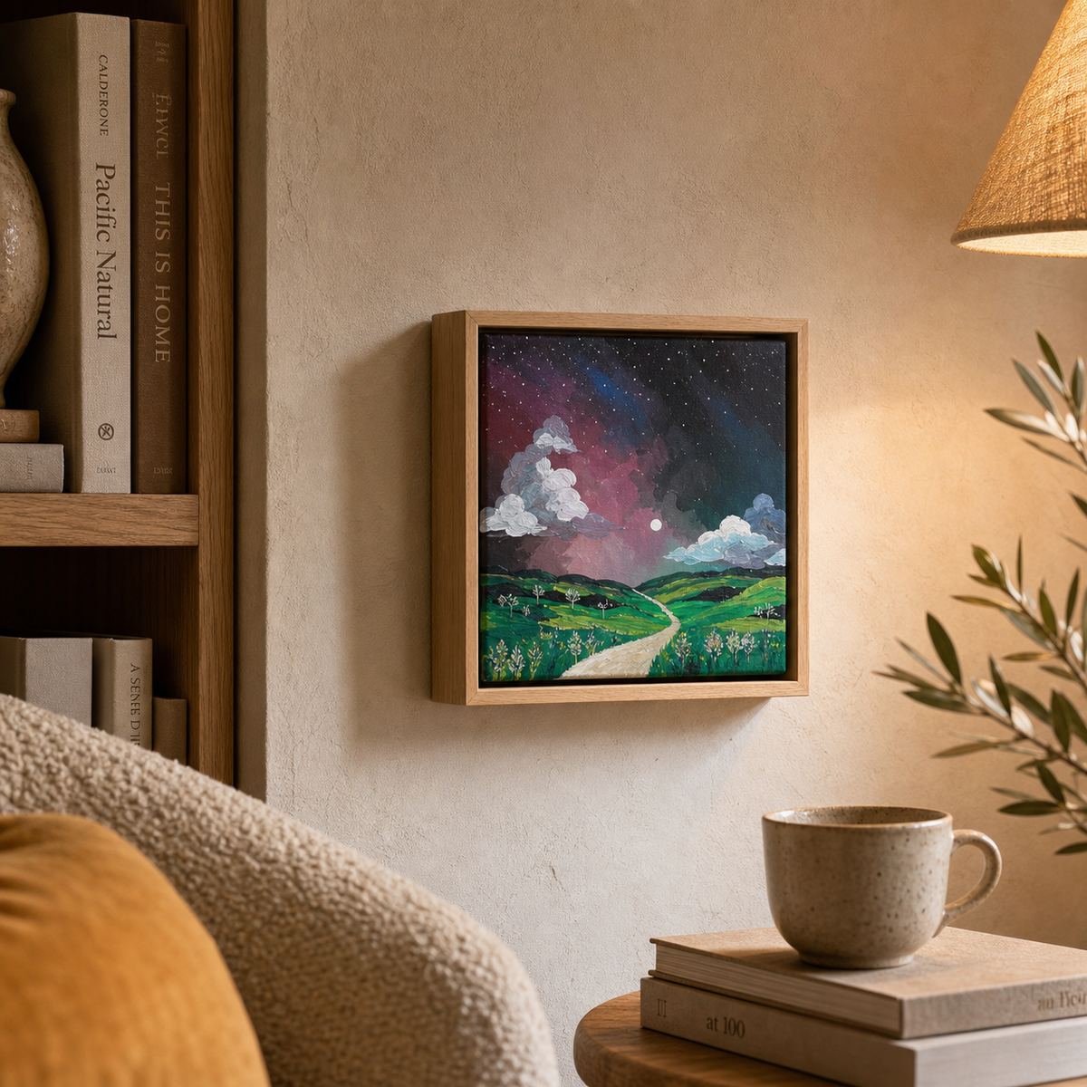 Aurora by Amber Miro, original night sky painting in pink, violet, and green, hanging beside a bookshelf in a reading nook