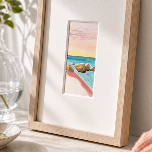 Beach Rocks by Amber Miro, original watercolor of shoreline rocks, angled view in an oak frame with white mat