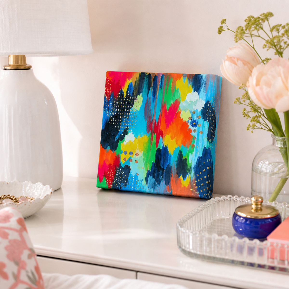 Blue Study by Amber Miro, original abstract in vivid blue, magenta, and green, leaning on a bathroom vanity beside flowers