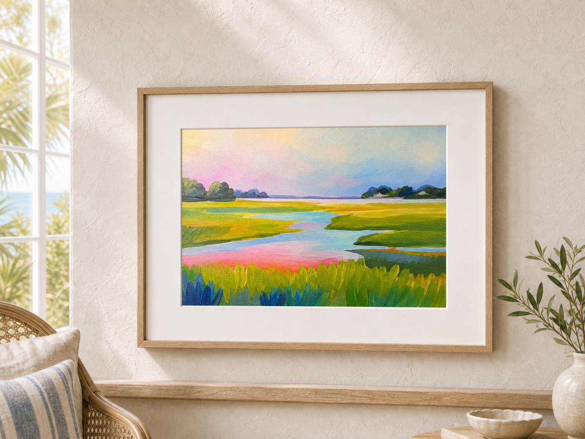 Sunset Marsh by Amber Miro, original marsh painting in pink and green-gold, framed in oak with a white mat beside a window