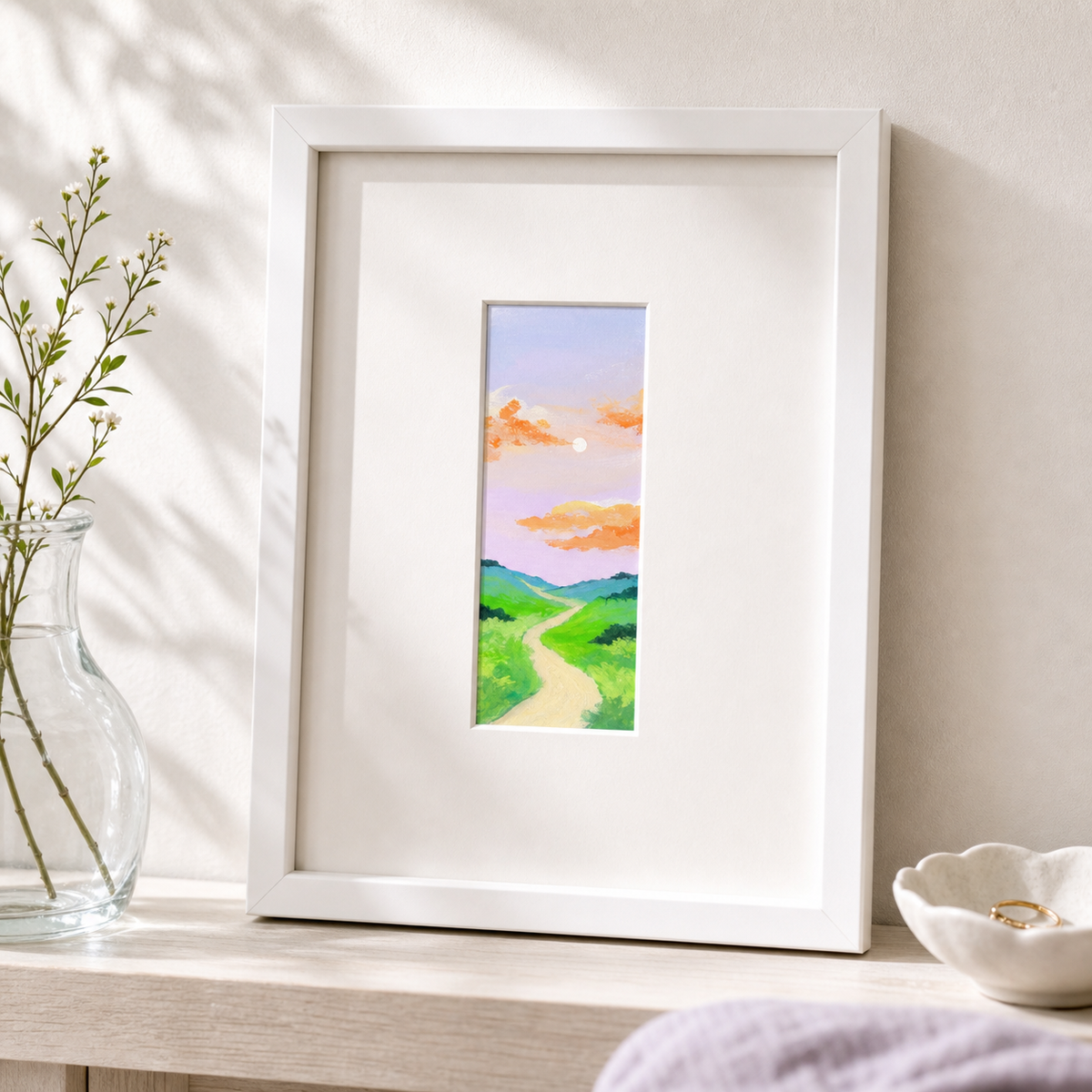 Purple Sunset by Amber Miro, original tiny painting of a purple and pink sky, in a white frame on a wooden table