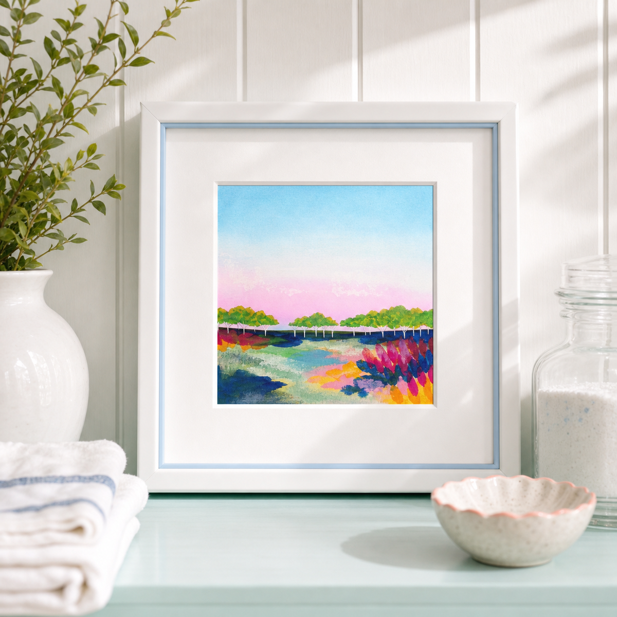 Walden Bridge by Amber Miro, original watercolor of the Walden Pond footbridge, in a white frame beside folded towels